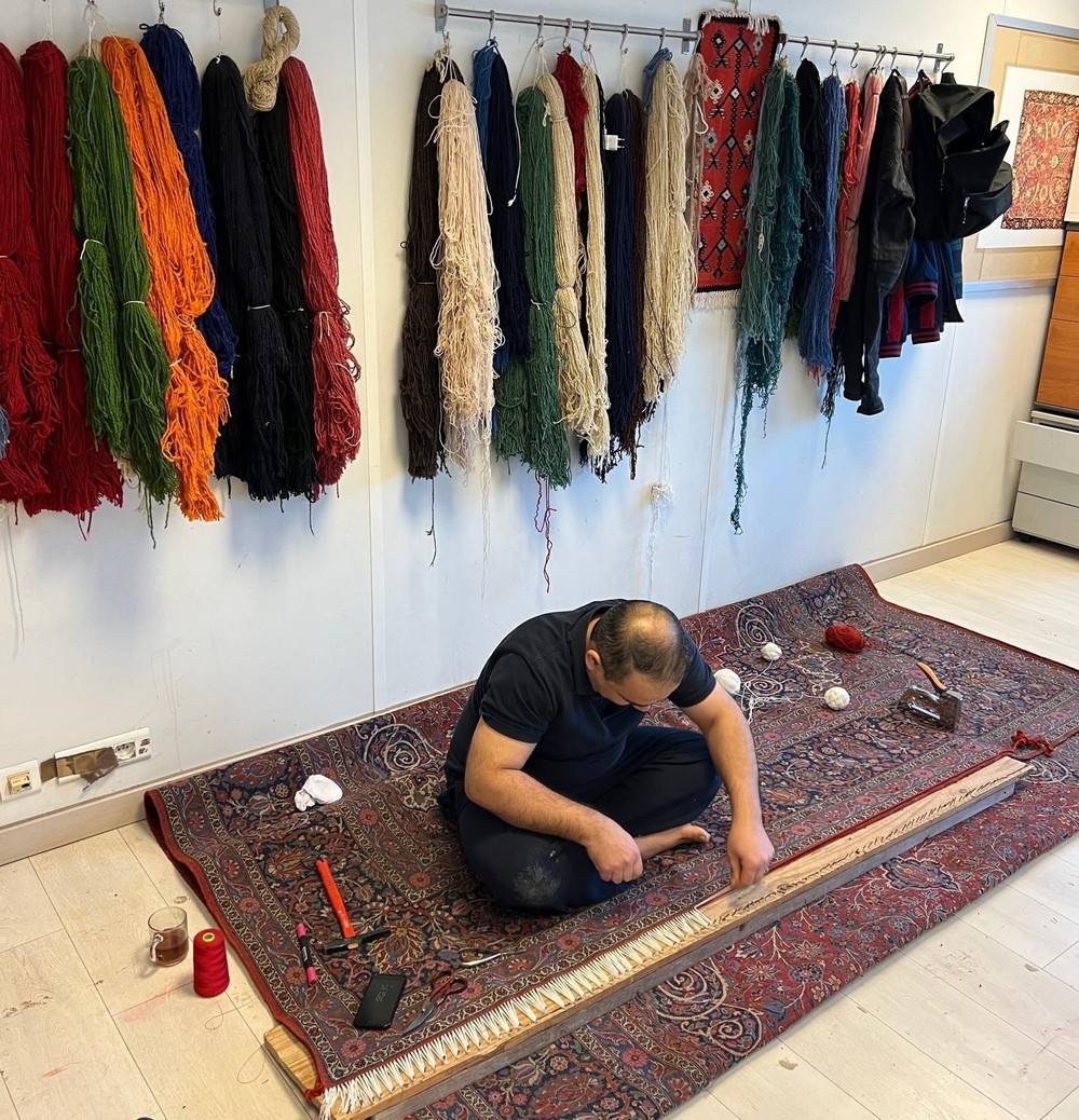 L’atelier : laines teintées au mur, tapis en cours de reprise au sol