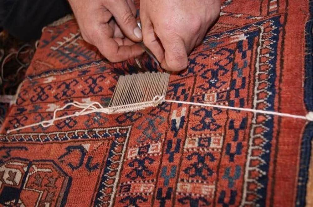 Le peigne de tisserand tasse la trame neuve à la densité du tapis d’origine.