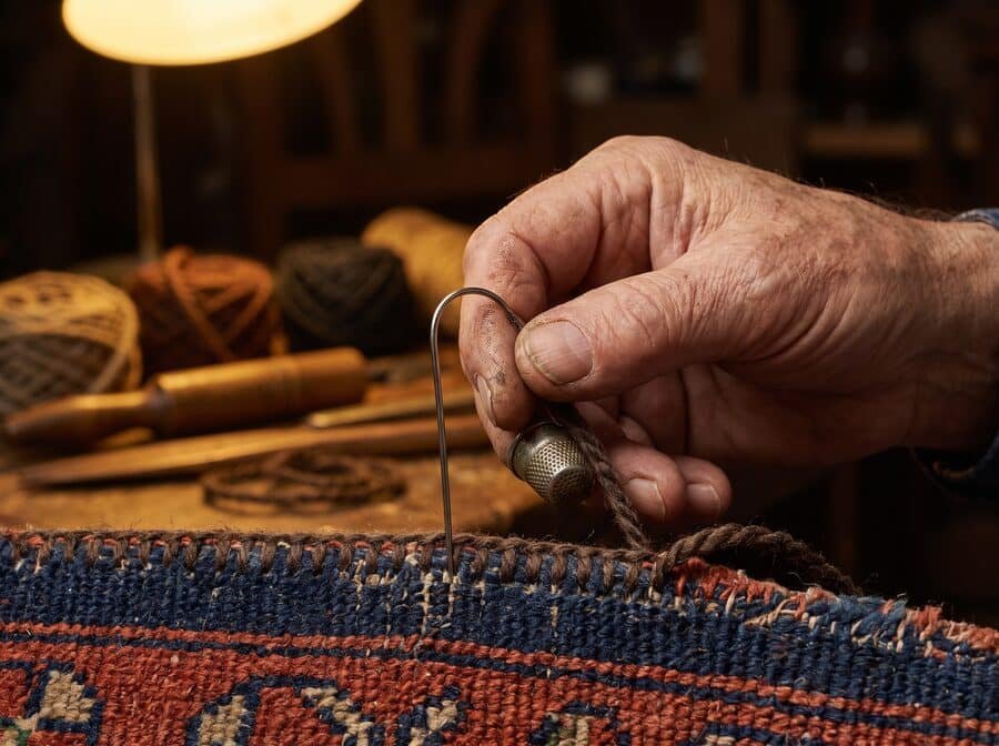Artisan refaisant la lisière latérale d’un tapis d’Orient au surjet main
